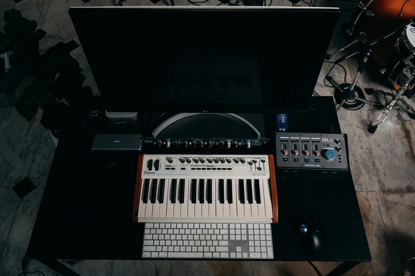 Un escritorio con un teclado, un sintetizador y equipo de audio dispuestos sobre él