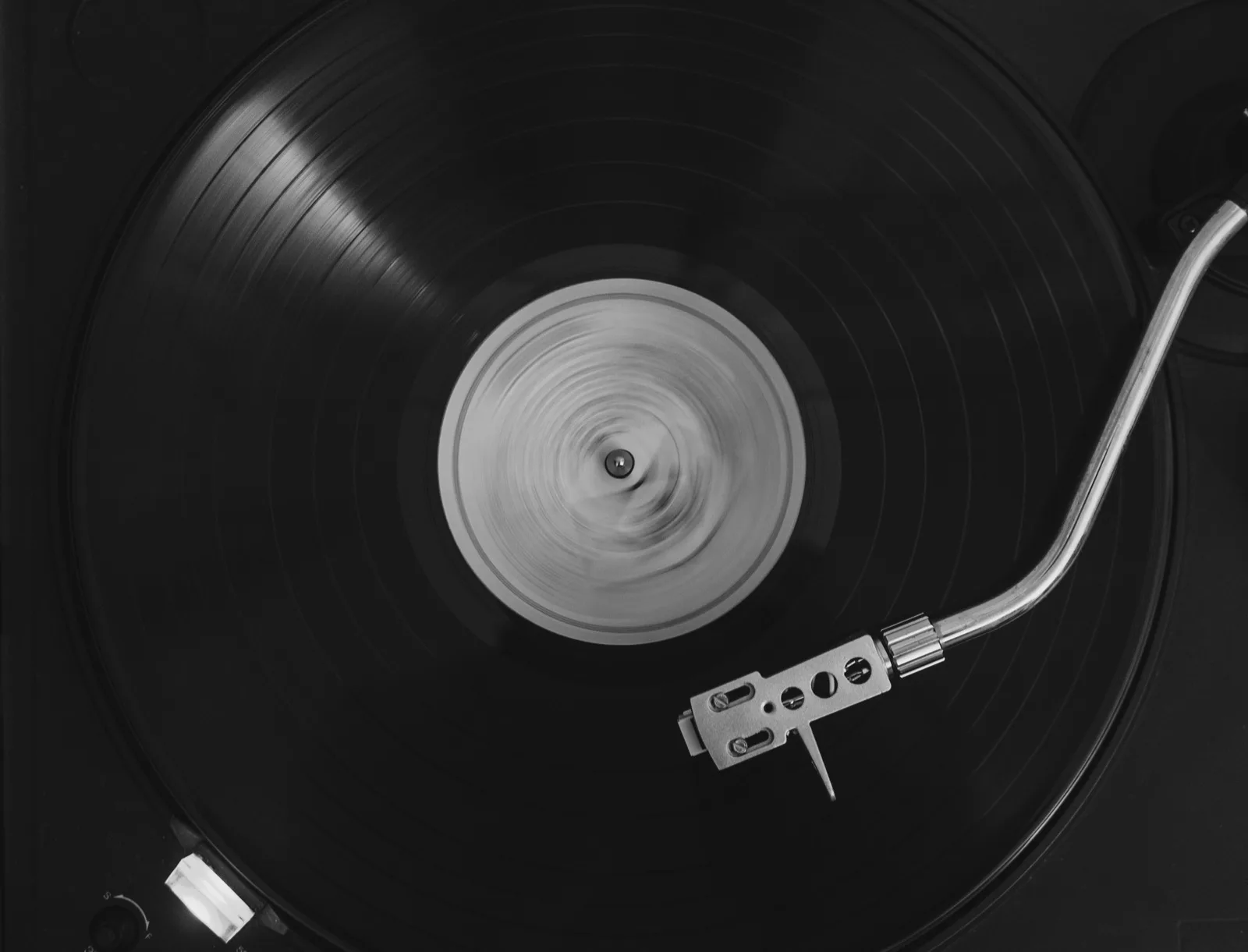 A black vinyl record turning on a platter, the tonearm resting in the groove